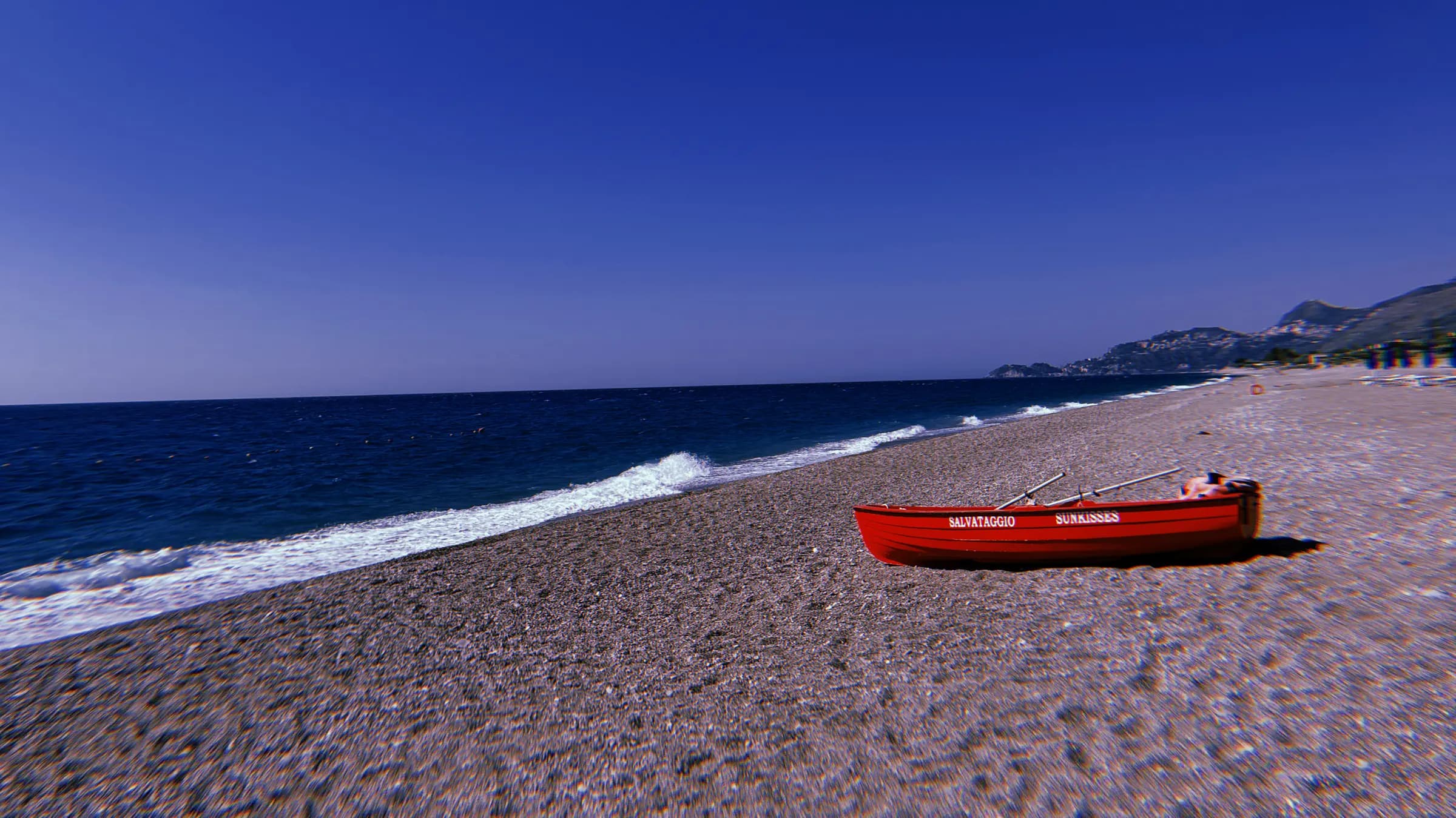 A red rescue rowboat on an empty pebble beach