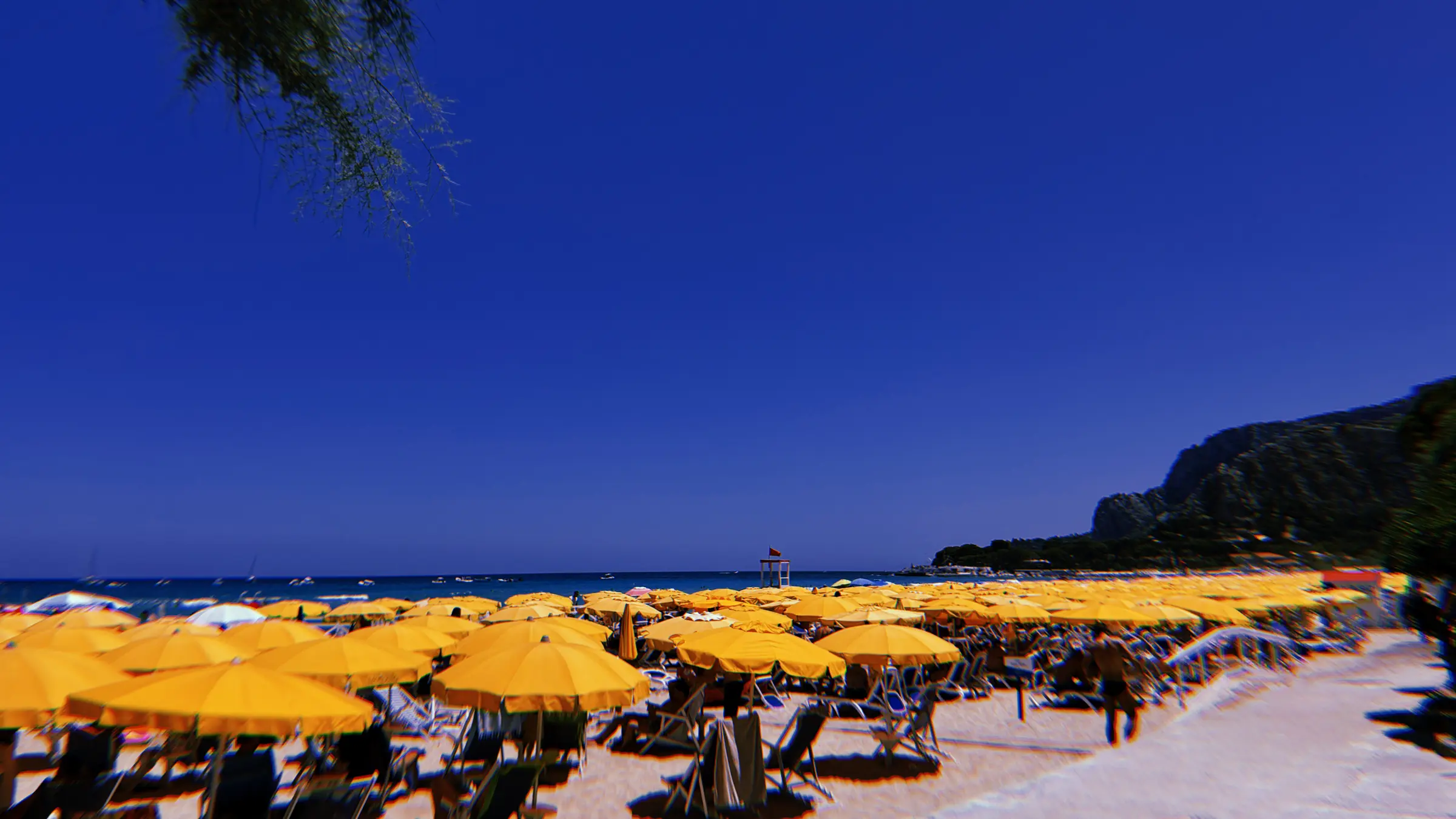 Rows of yellow beach umbrellas under a deep blue sky